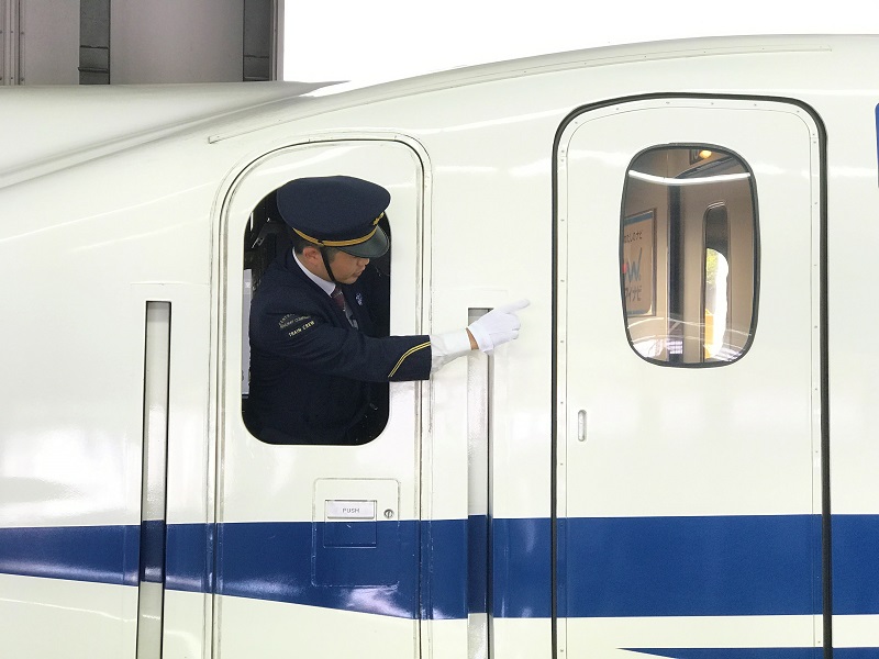 出発進行の合図をする東海道新幹線の車掌の無料写真