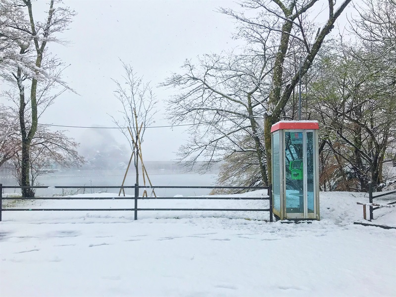 雪が降り積もる湖畔の電話ボックスの無料写真