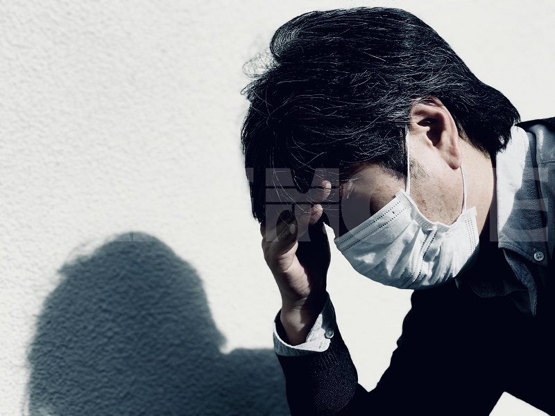 新型コロナウイルス？インフルエンザ？発熱と頭痛の症状に悩まされるマスク姿の男性の無料写真
